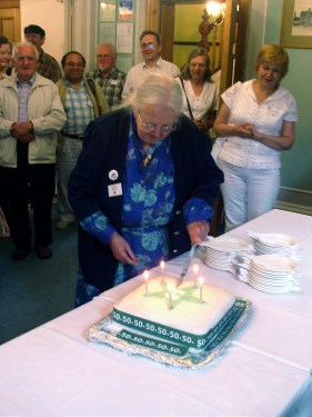 Marjorie Boulton cuts the cake; photo Vilĉjo Walker